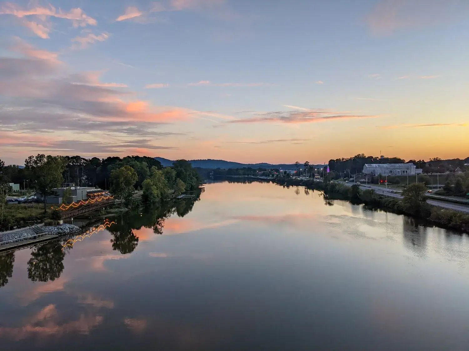 Scenic evening  sunset view of Gadsden’s riverwalk  river‐front district by Coosa River — emphasizes water’s proximity to urban areas.
