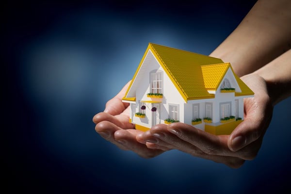 Human hands holding model of dream house