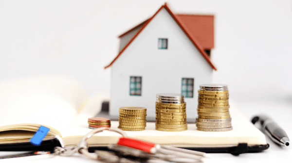 property value showed by a miniature home behind a stack of coins