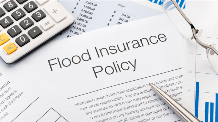 flood insurance policy paper beside a calculator and glasses